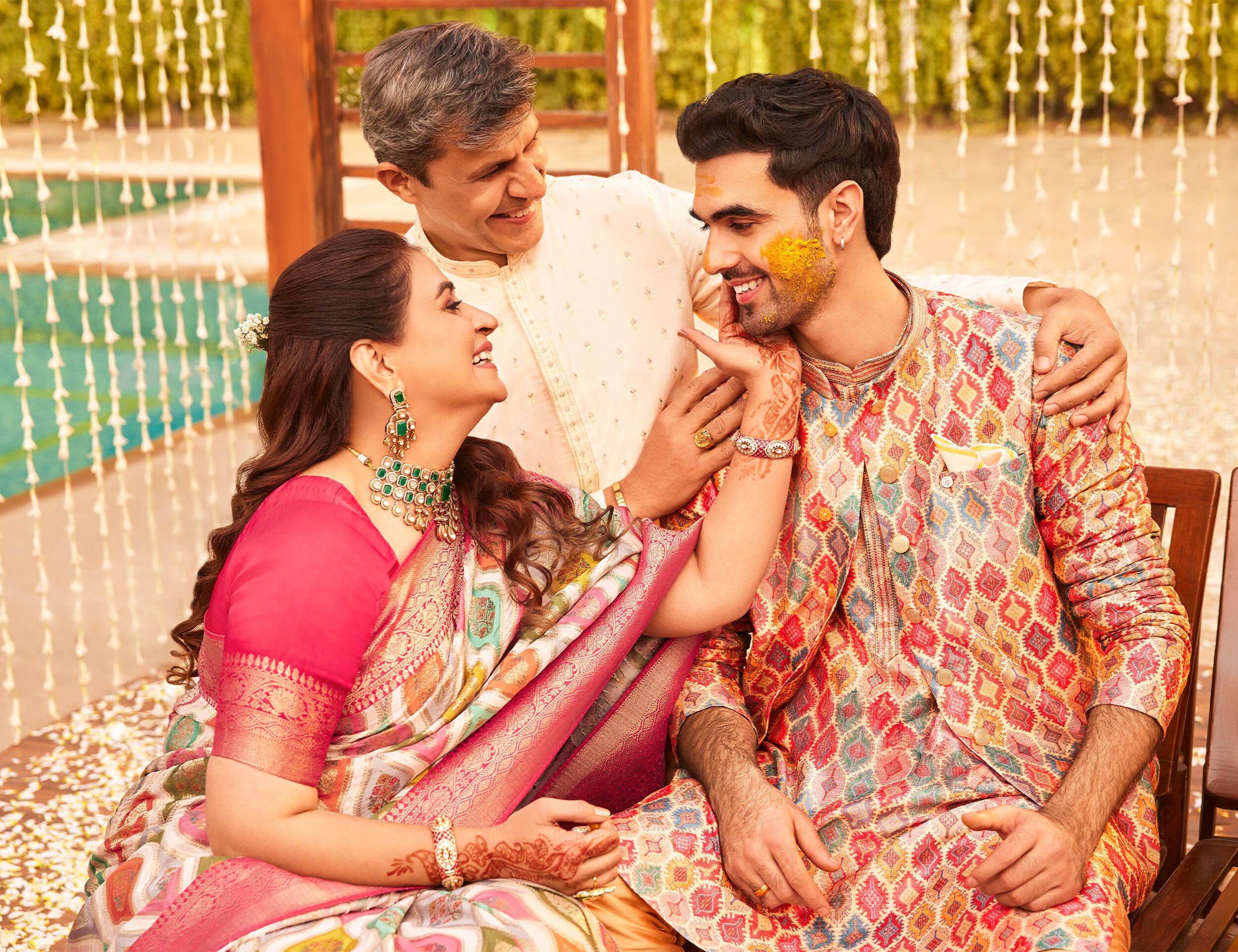 Mother celebrating Mother&rsquo;s Day with her son and family in festive ethnic wear, sharing a joyful moment in a decorated setting.